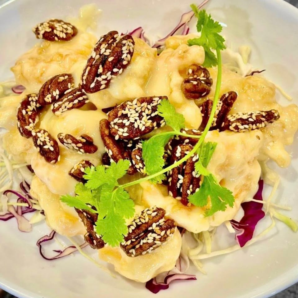 Honey walnut shrimp with sesame seeds and cilantro, served over shredded cabbage.