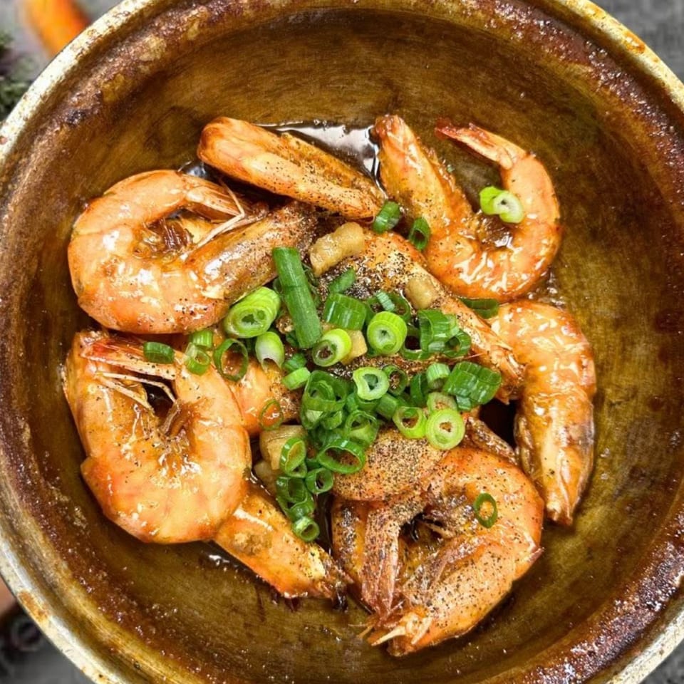 Close-up of Kin’s Restaurant's shrimp dish, garnished with green onions and black pepper.